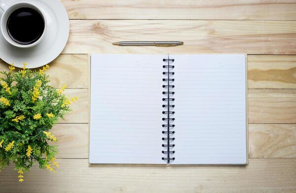 Open notebook with a pen on a wooden table